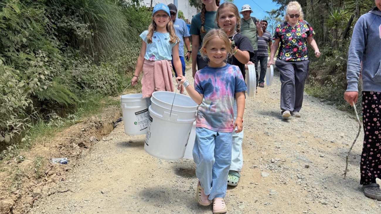 A girl carrying her family’s new filter bucket home along a mountain road