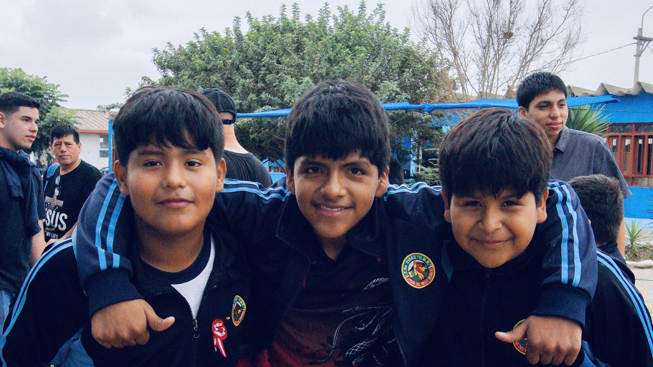 Three boys with their arms around each other, laughing
