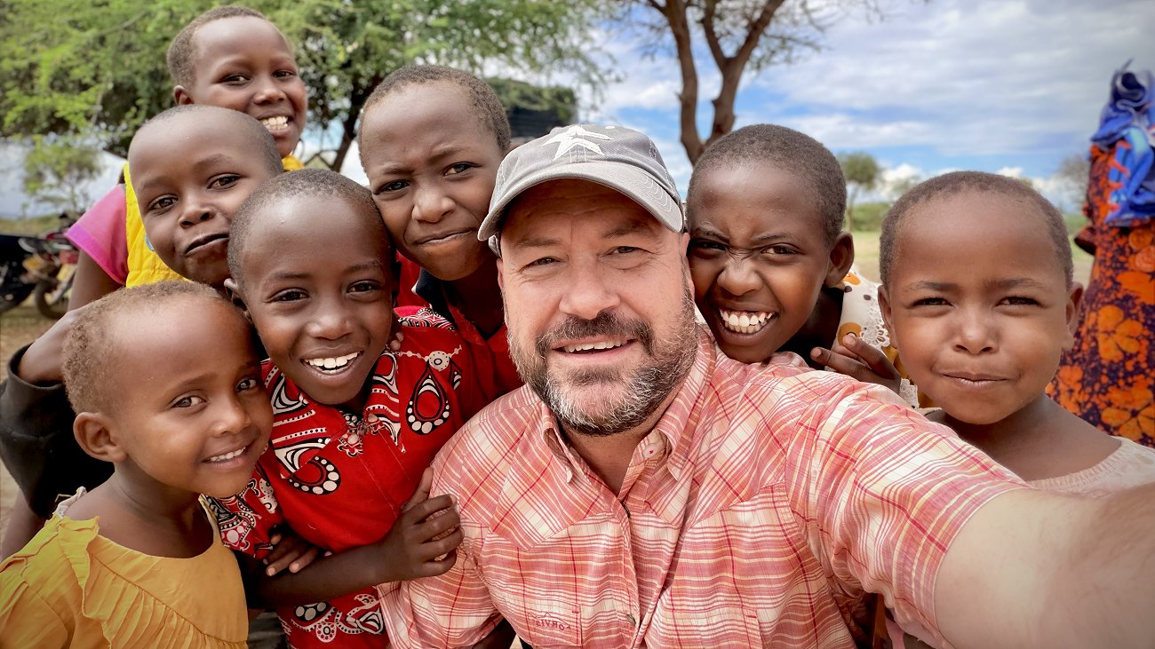 Danny Green with a group of Maasai children under an acacia tree in Kenya
