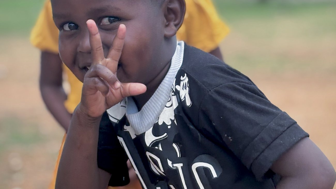 A young boy smiling and making a peace sign