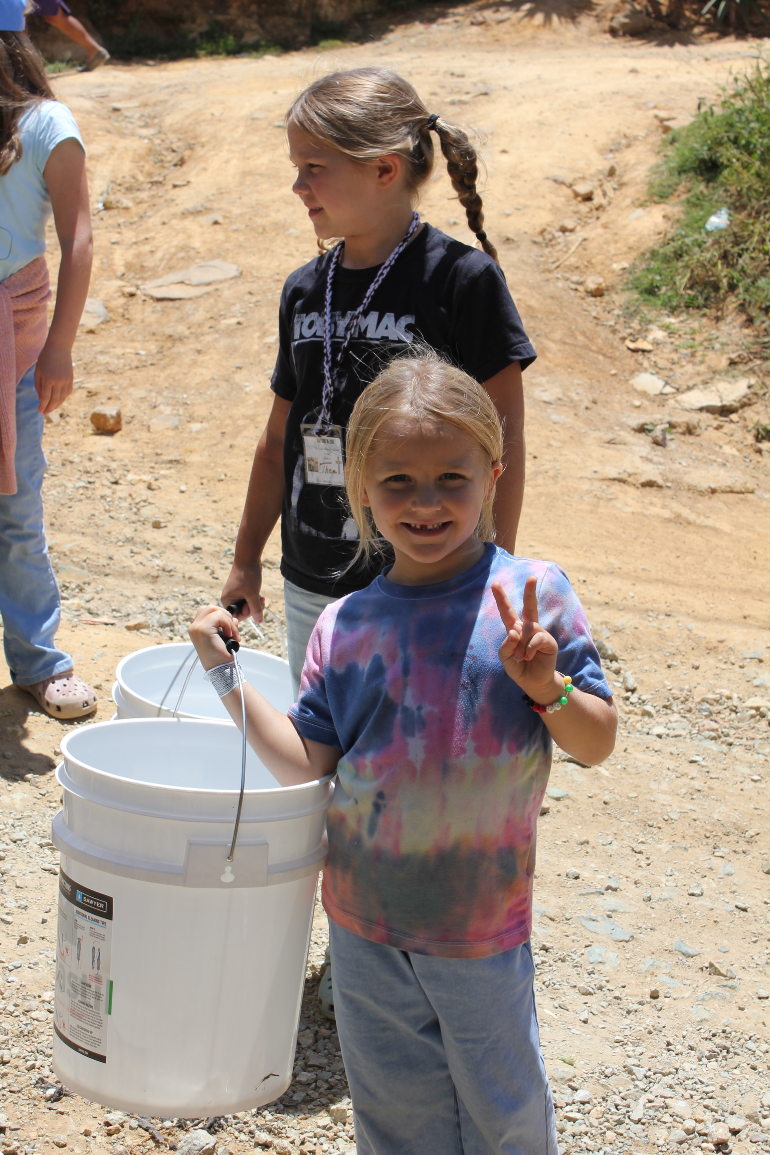 A young volunteer smiling as she carries a water filter bucket